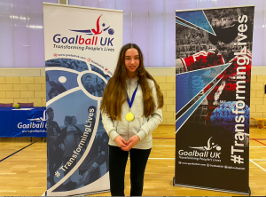 Ciara McDonagh stood wearing her well earned Player of the day medal in front of two Goalball UK banners.