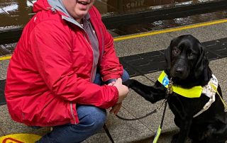 Michael Allan and guide dog Olga at a train station. Michael and Olga have made a business agreement which has ended up in a hand paw shake.