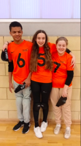 New College Worcester novice team huddled together smiling. From left to right, Rico, Ciara, and Phoebe.