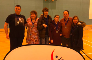 Michael with his VI Bees teammates, and their medals, stood in front of a pop up Goalball UK banner.