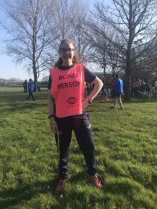 Keira Mills stood in a field at her local parkrun with trees behind her.