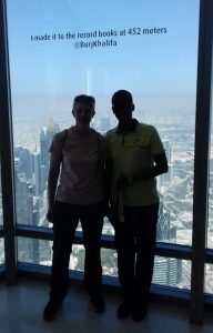Kathryn Fielding and Yahye Sayid standing together on the top level of the Burj Khalifa, blue skies for days!
