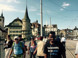 Yahye Sayid standing for a photo in Switzerland with a church behind him with people walking past.