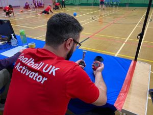 A goalball activator concentrating heavily on his stopwatch to record the 10 second timer.
