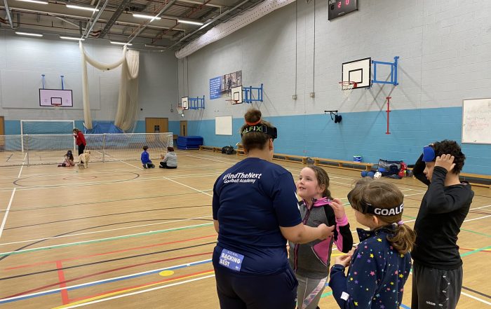 Hammersmith Junior Day, with Alex Ulysses talking to 3 junior players who are all stood in their team area.