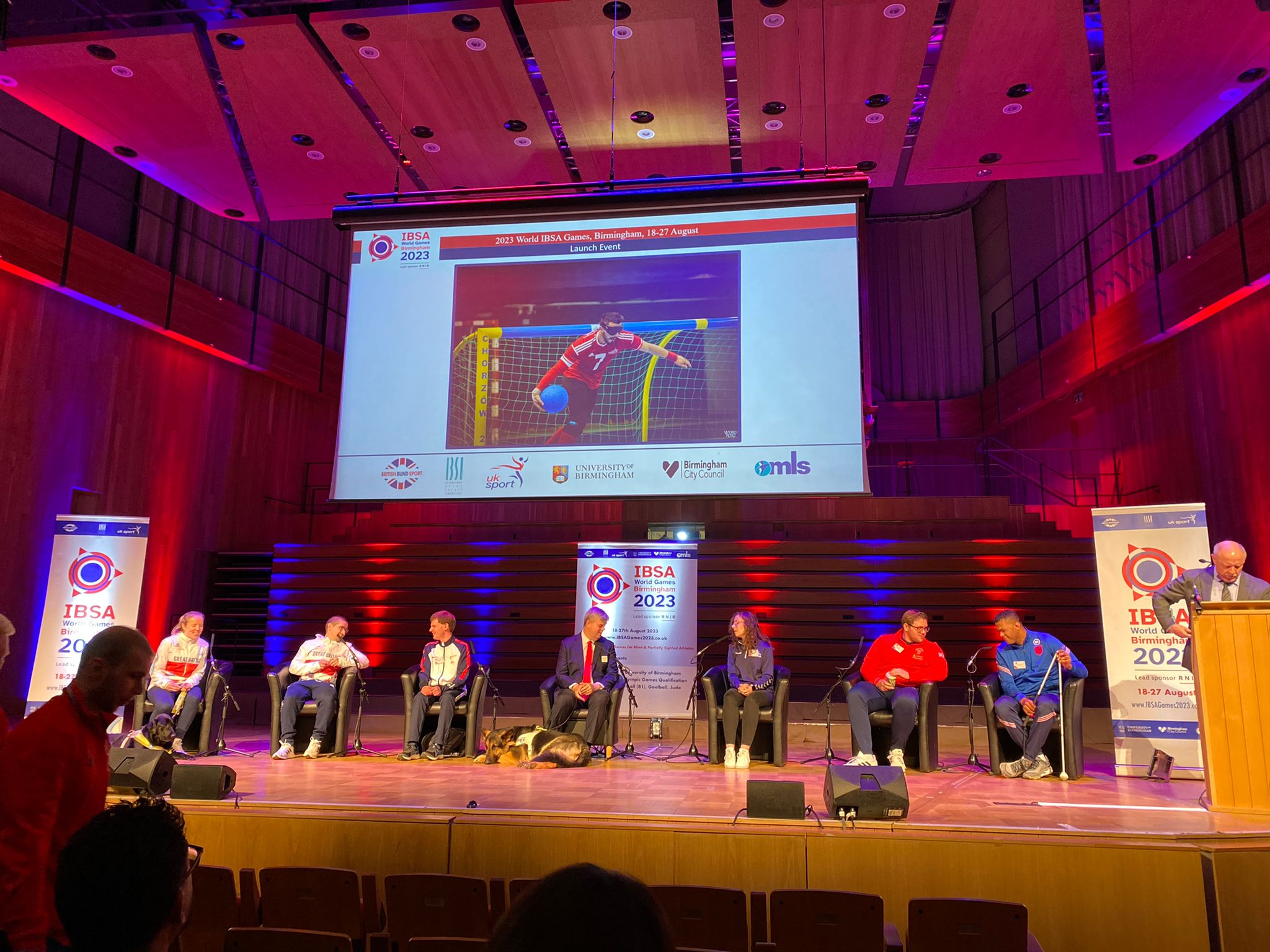 IBSA World Games launch with speakers on a stage, and goalball being showcased behind them on a large screen with Dan Roper playing for GB in view.