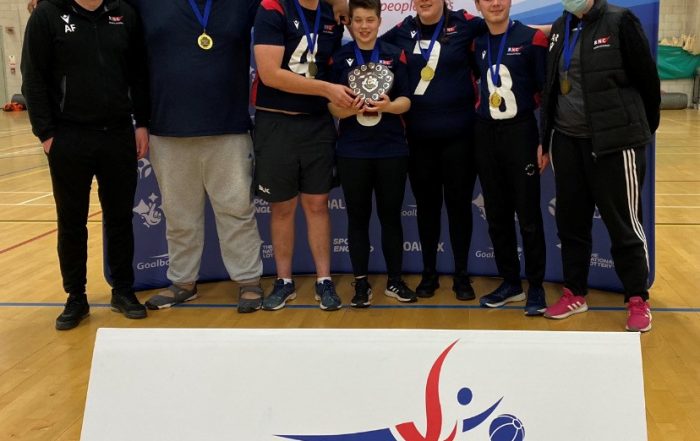 RNC Academy players holding the Novice Shield with the Goalball UK board in front of them.