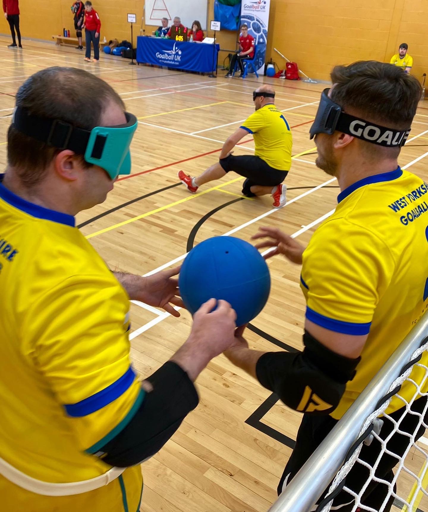 Two West Yorkshire players on the left post, with one player holding the goalball preparing to run to shoot.
