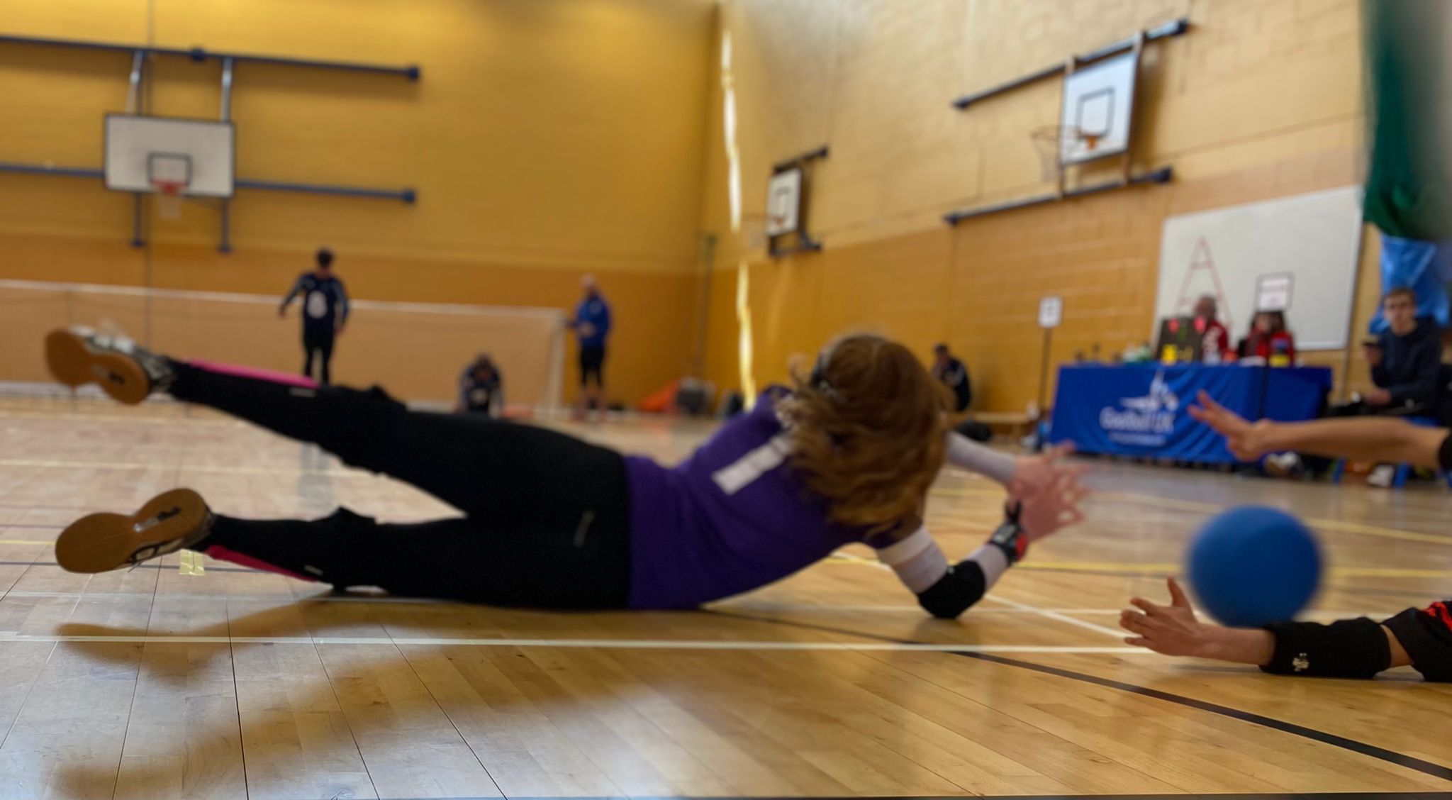 Chelsea Hudson of York St John diving out to the right whilst playing in centre to save the goalball. The right wing player has saved it with their hands in view in the photo.
