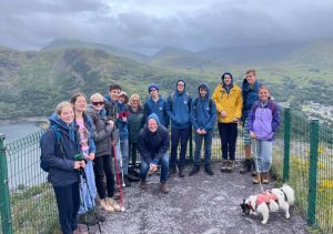 Winchester players, parents and coaches out in a mountain area on a outdoor adventure trip. It's quite drizzly so everyone is wearing raincoats, but smiles all round!