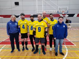 West Yorkshire Intermediate Trophy team with players wearing yellow jerseys, with coaches Kathryn and Connor wearing blue West Yorkshire hoodies.