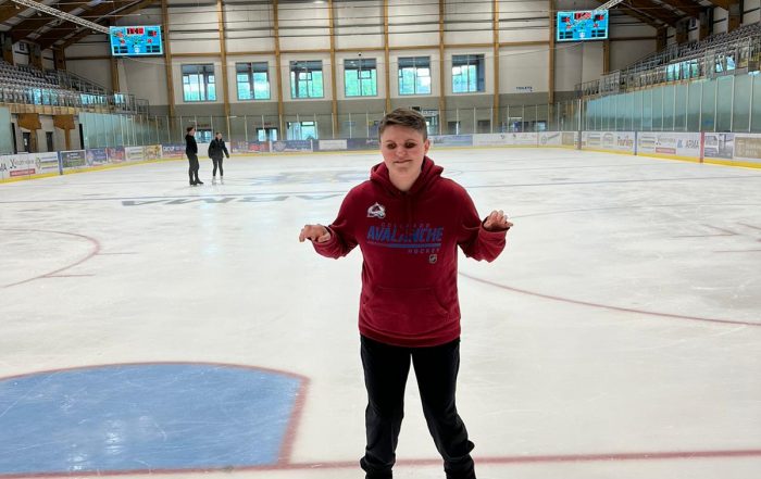 Connor ice skating, he is holding his hands up to balance with people skating behind him.