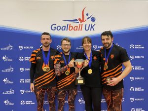 Fen Tigers Elite National Champions group photo with Dom, Joe, and Dan Roper standing with Emma Evans, all with medals around their necks and the trophy!