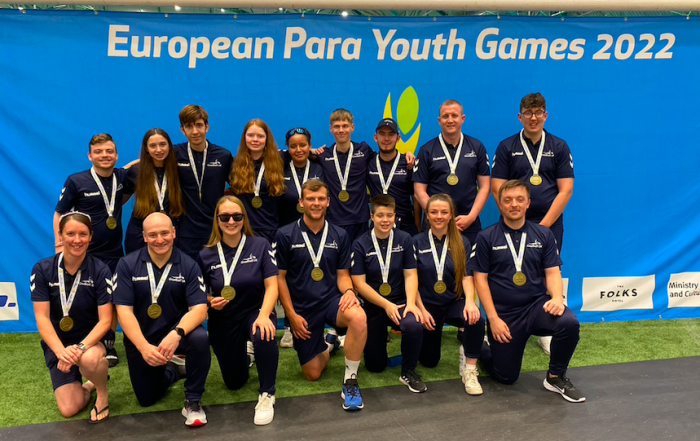 GB Men and Women's squads coming together for a group photo at the closing ceremony of the European Para Youth Games 2022. Everyone's wearing their bronze medals and their navy blue polos.
