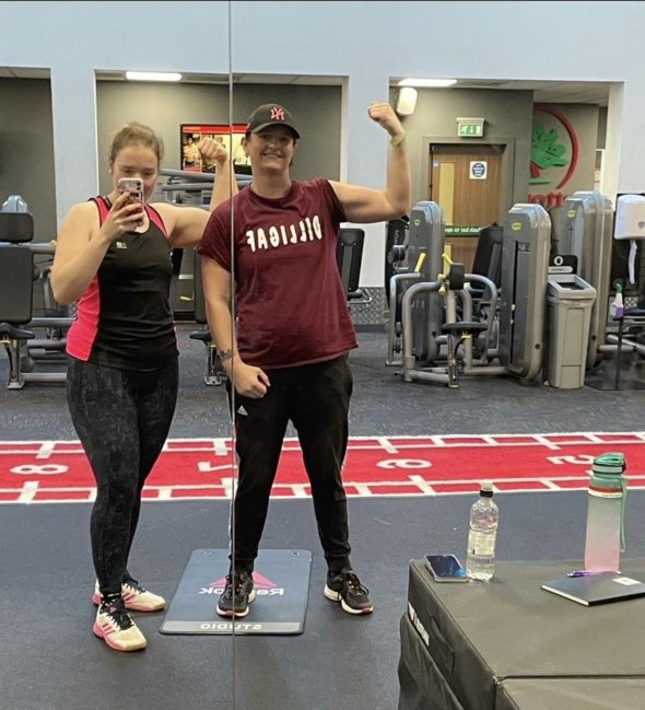 Susan and Lois Turner standing together in a gym both flexing their biceps!