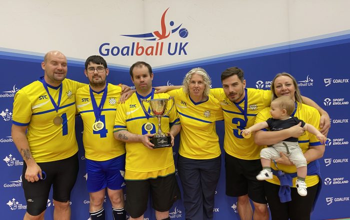 West Yorkshire Intermediate National Finals group photo in front of a Goalball UK banner with all players and coaches, who have their medals and the trophy!