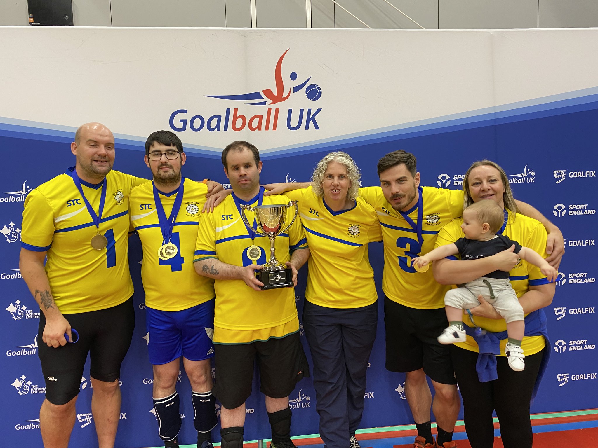West Yorkshire Intermediate National Finals group photo in front of a Goalball UK banner with all players and coaches, who have their medals and the trophy!