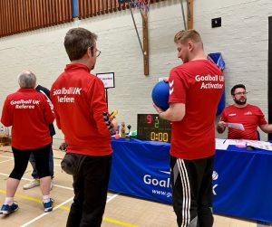 An activator holding the goalball as a referee inspects it