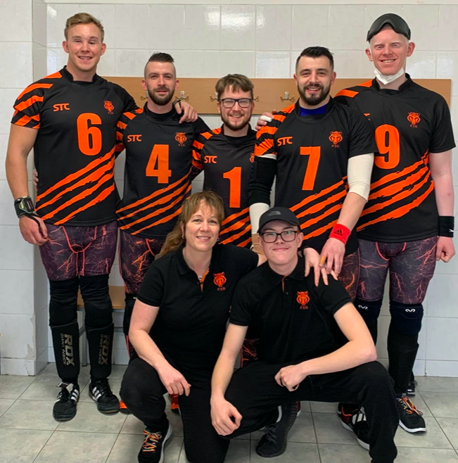 Fen Tigers group photo ahead of their first S E G L game. Everyone is wearing their black Tigers shirt, which has claw marks going across the bottom half.