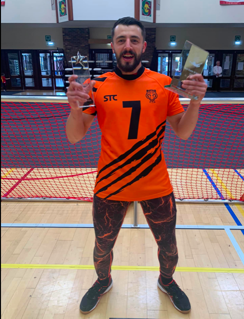 Dan posing in front of a goal in his orange Fen Tigers top with his highest goalscorer trophy!