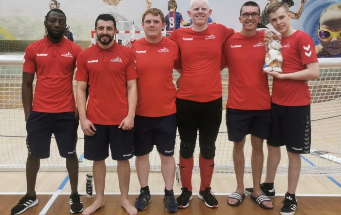 Six goalball players from GB Men's squad stood for a team photo. They are all wearing red Goalball UK t shirts