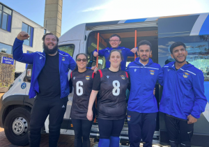 Birmingham goalball club pose for a group photo outside. They are stood infront of their van.