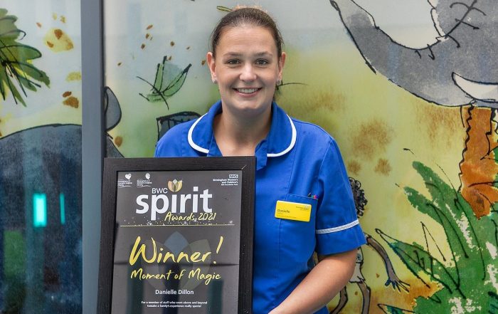 Dani Dillon in a blue nurse's uniform holding up an award