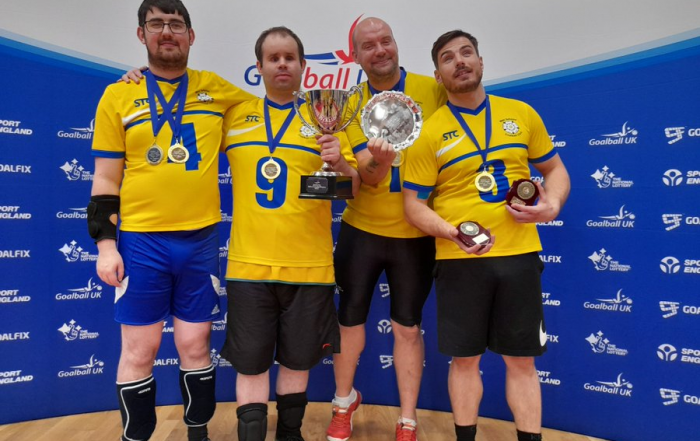 West Yorkshire Goalball Club team photo with four players including Nick. They are holding up their medals and a trophy