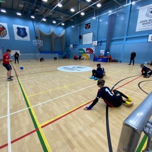 Wide view of the goalball court in action from behind the goal net