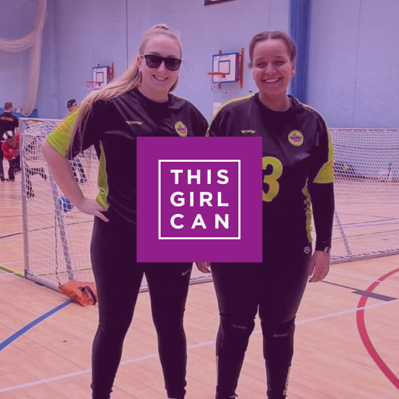 Two female goalball players are stood posing for the camera in the background. In the foreground is the This Girl Can logo which is a purple square with 'This girl can' written in white text