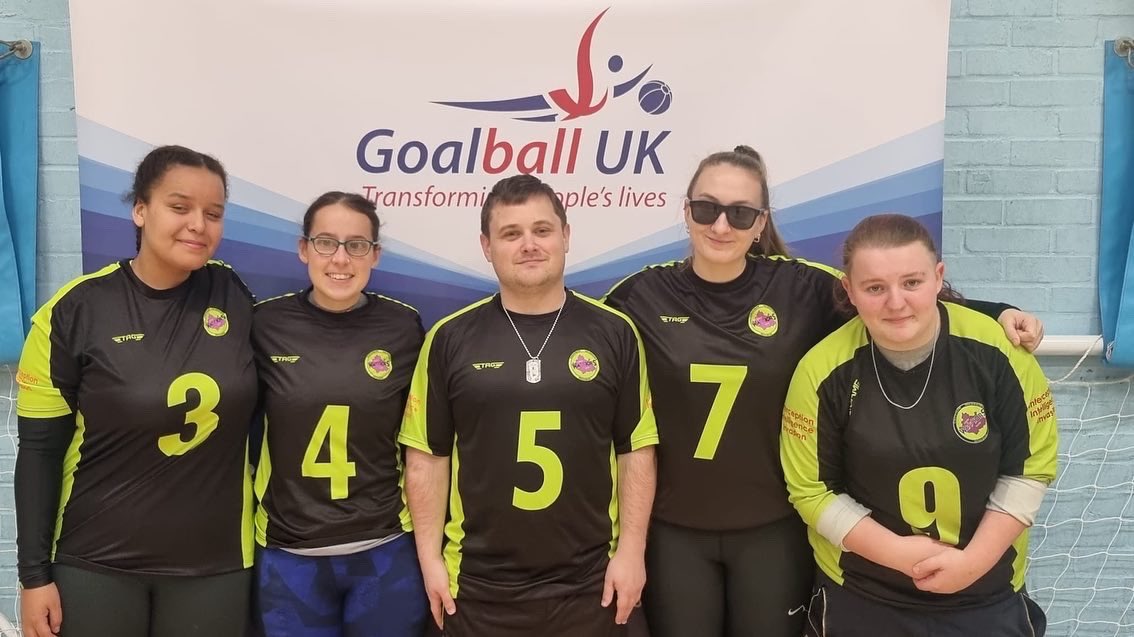 The Croysutt Warriors team smiling for a photo in front of a Goalball UK banner