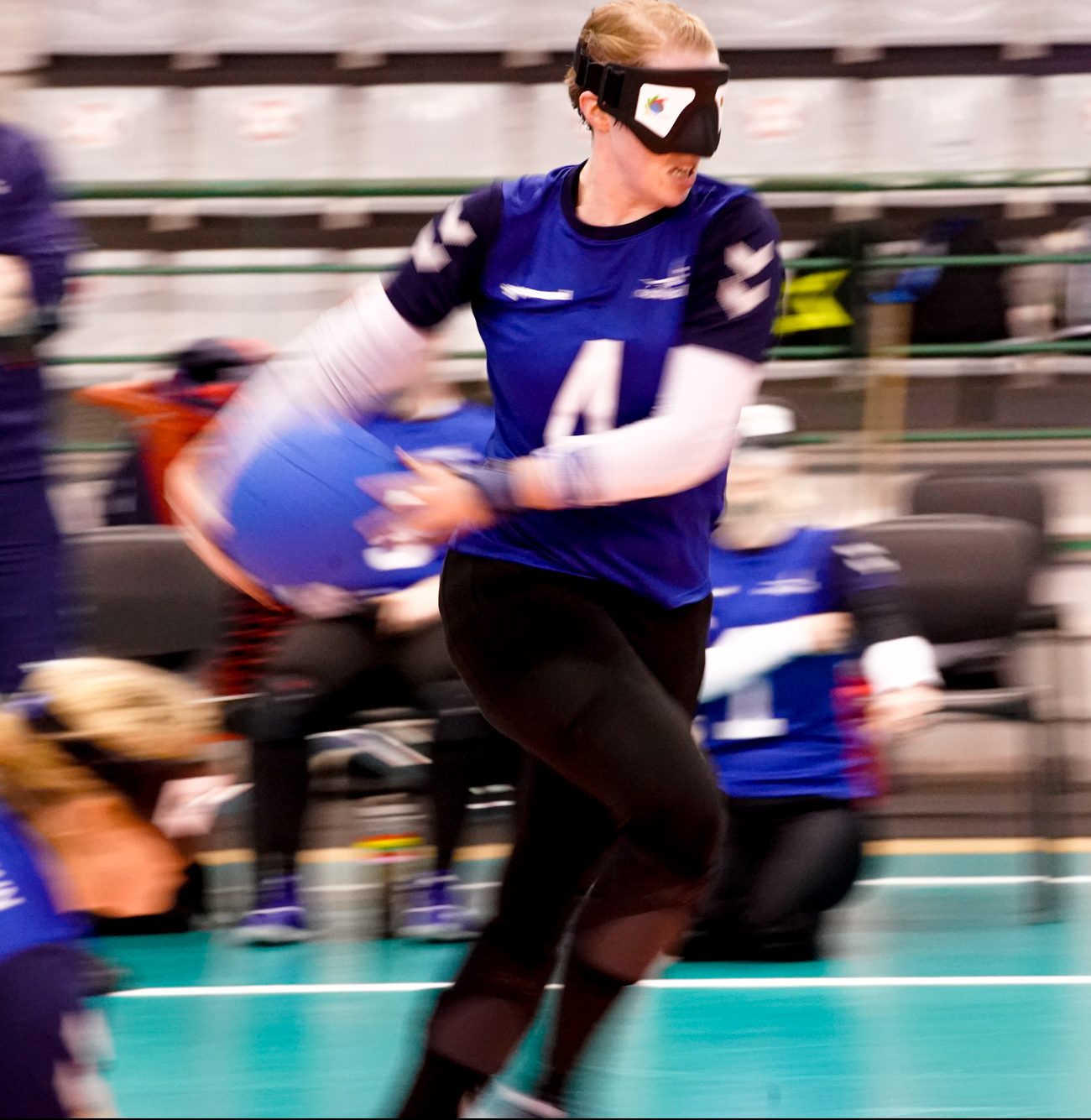 Georgie Bullen playing for GB Women at the 2022 World Championships. She is wearing blue GB kit and about to throw the ball to the opposing team.