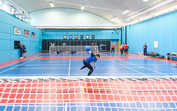 A female GB goalball player is centre of the court, with her arm drawn back ready to throw the ball