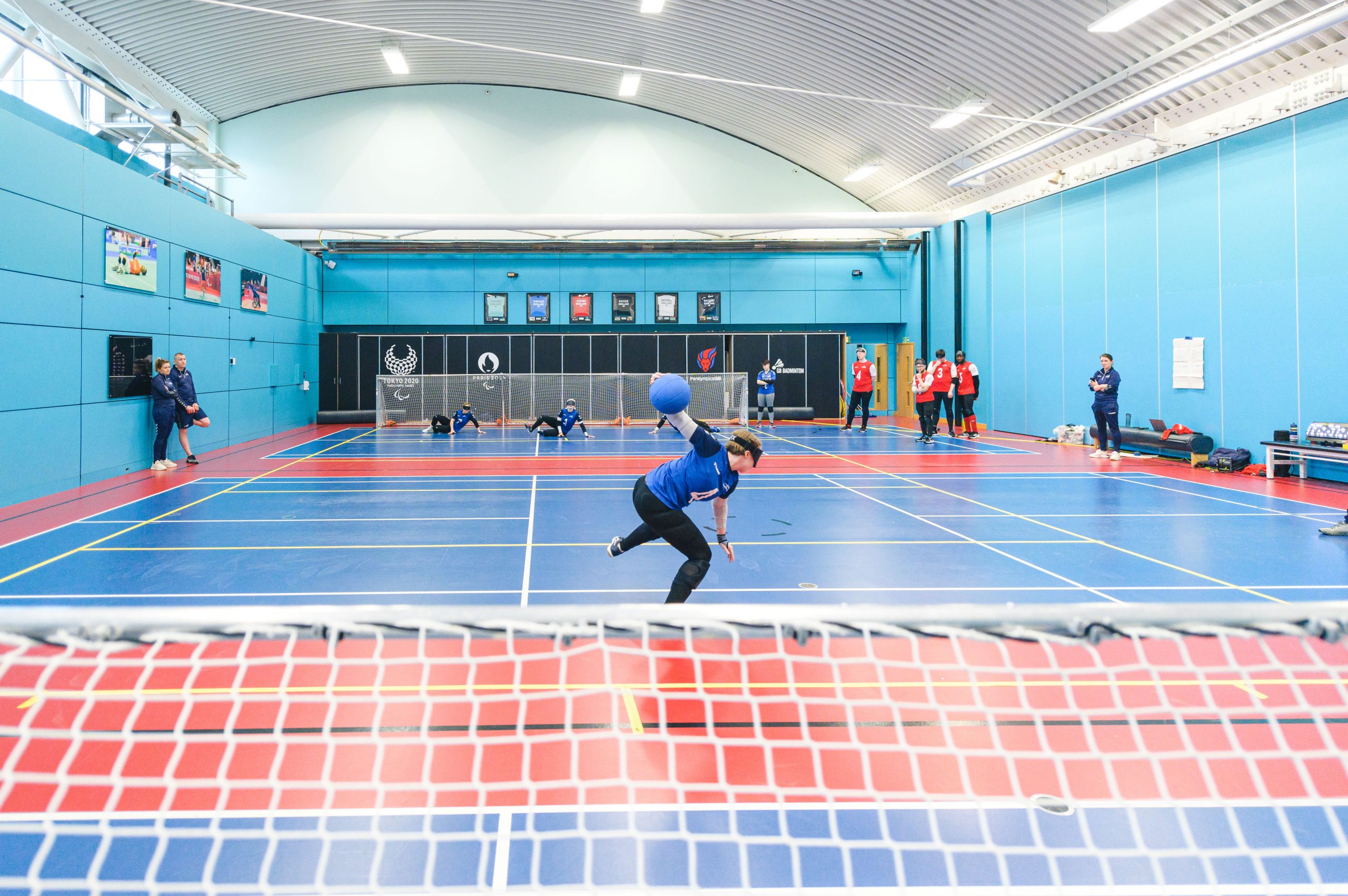 A female GB goalball player is centre of the court, with her arm drawn back ready to throw the ball
