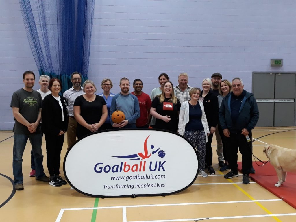 A group of people stood behind a Goalball UK banner having just completed a course