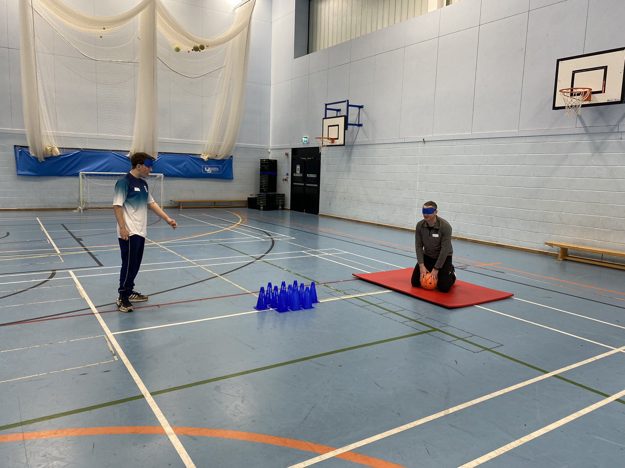 Action shot of two candidates on the Goalball School Leaders Course practicing one of the activities: ten cone bowling.