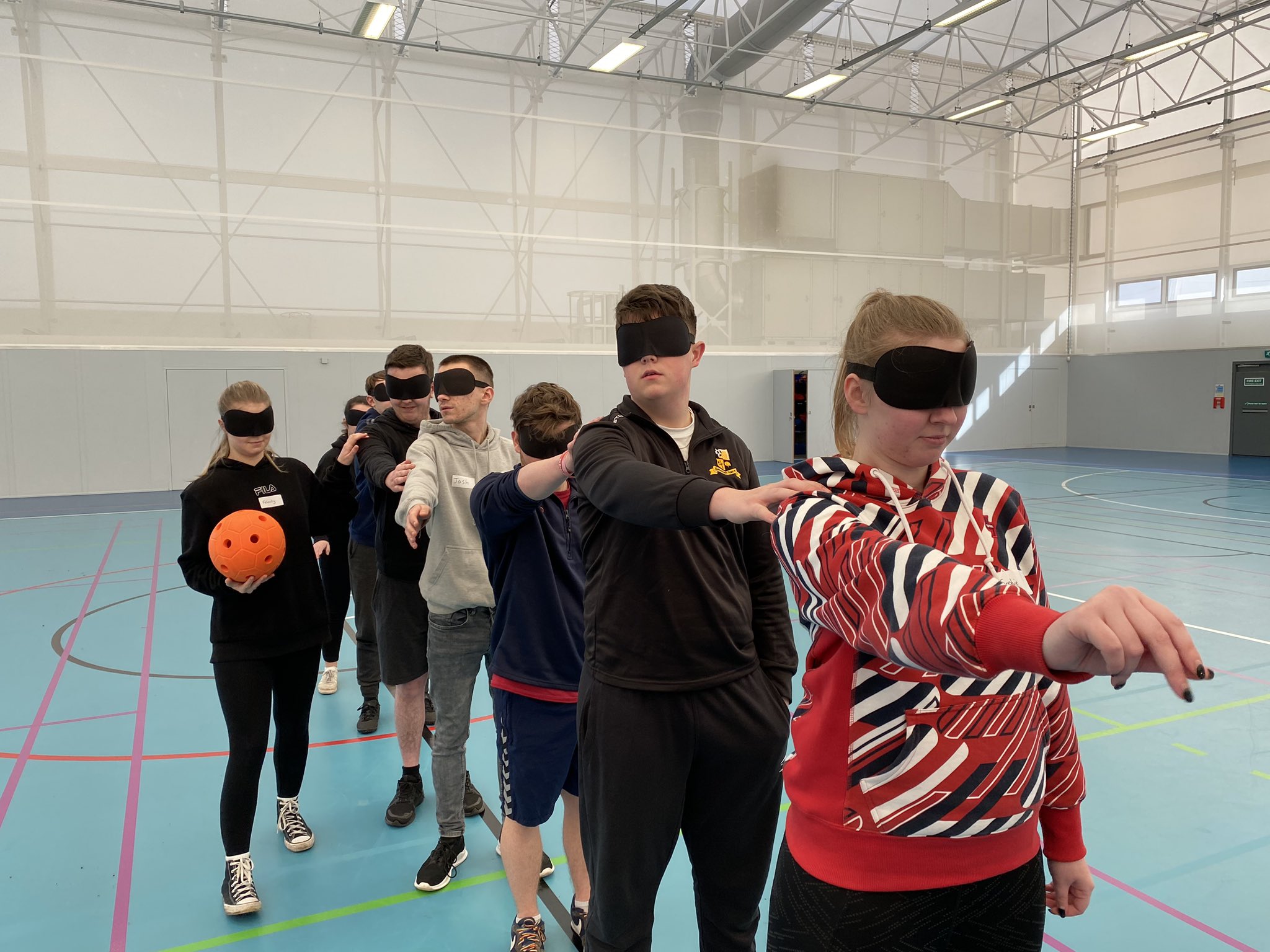Action shot of the Goalball School Leaders, with the candidates practicing their communication and teamwork skills in a game of ‘Over and Under’ wearing eyeshades.