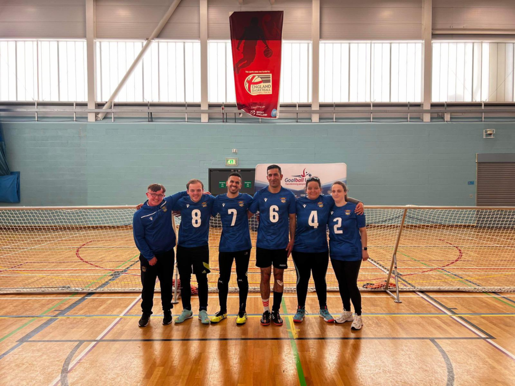 A group photo of Birmingham Goalball Club. They are stood in a line with arms around each other