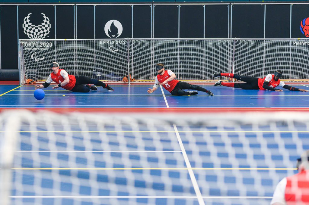 Action shot of GB Men in training. Three players are captured preparing to defend a goal with their bodies