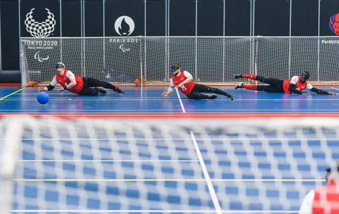 Action shot of GB Men in training. Three players are captured preparing to defend a goal with their bodies