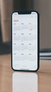 black android smartphone on brown wooden table with the calendar app open
