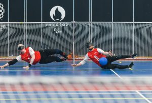 Action shot of two male goalball players defending a goal with their body