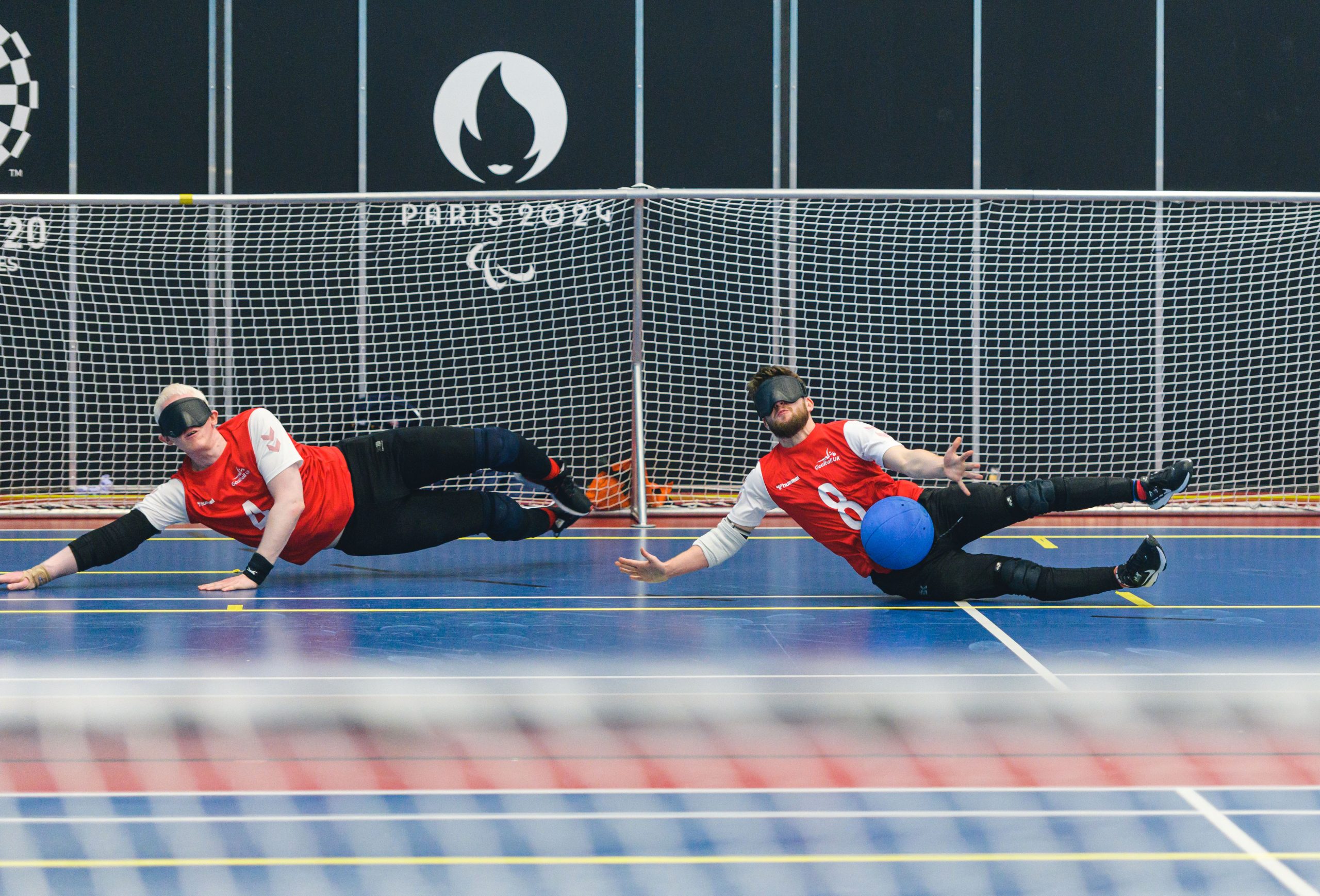 Action shot of two male goalball players defending a goal with their body