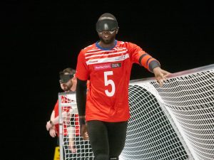 GB Men athlete Caleb Nanevie is stood at the goal during a game with one arm on the top bar