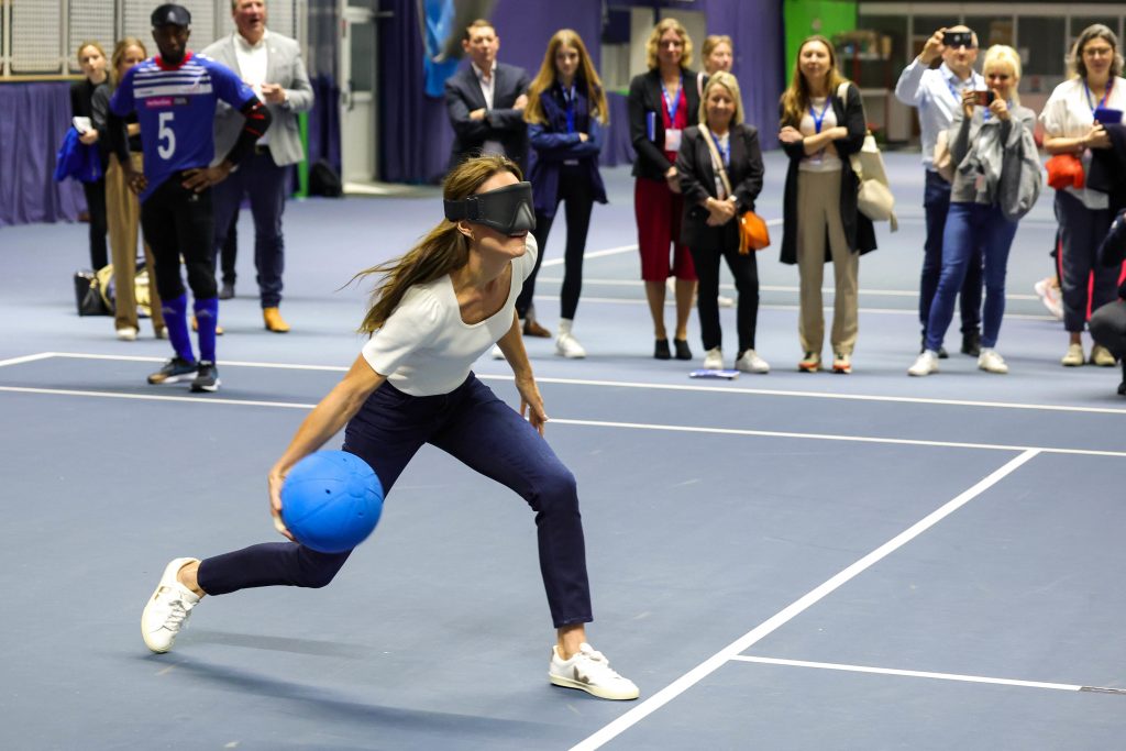 The Princess of Wales, Kate Middleton, shoots for a goal wearing a white top and blue jeans.