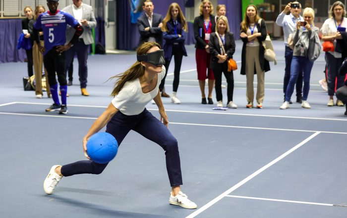 The Princess of Wales, Kate Middleton, is wearing eyeshades and is throwing the goalball to shoot for a goal