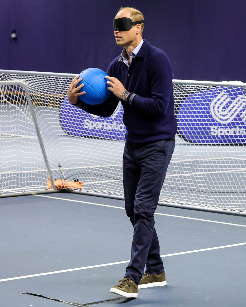 Prince William stands holding a goalball and wearing eye shades, ready to shoot