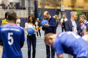 The Prince and Princess of Wales are stood on a sports court holding a goalball each