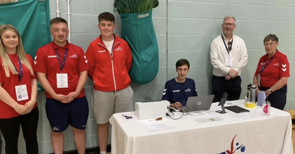 Felicity on the left of the photo is stood with other staff from Goalball UK in the sports hall for the Goalfix Cup 2023