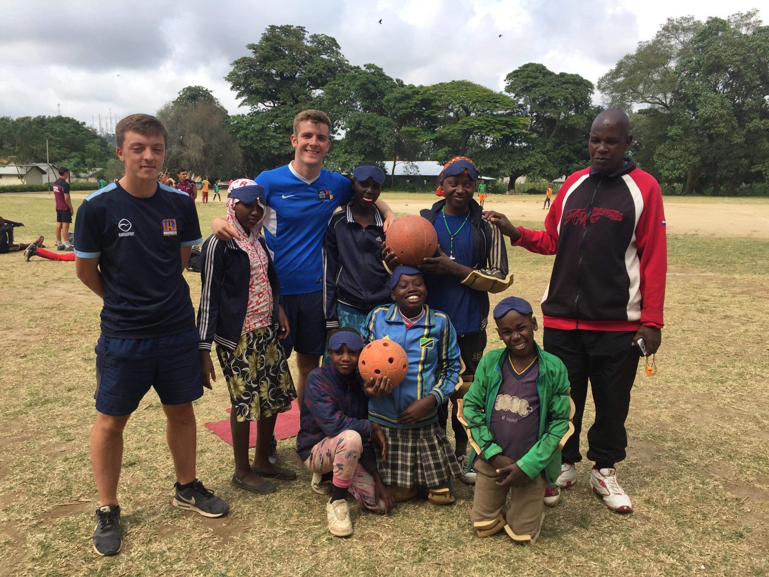 Alex Cockerham on the left of the photo stands with a group of children and other teachers during an outdoor goalball session in Tanzania